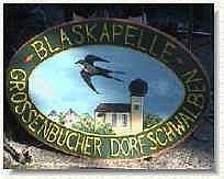 Holzschild mir dem Logo der Blaskapelle